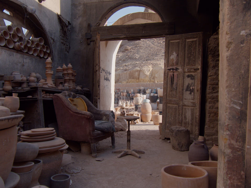 Pottery and an old armchair inside a Cairo workshop, looking through an arched doorway