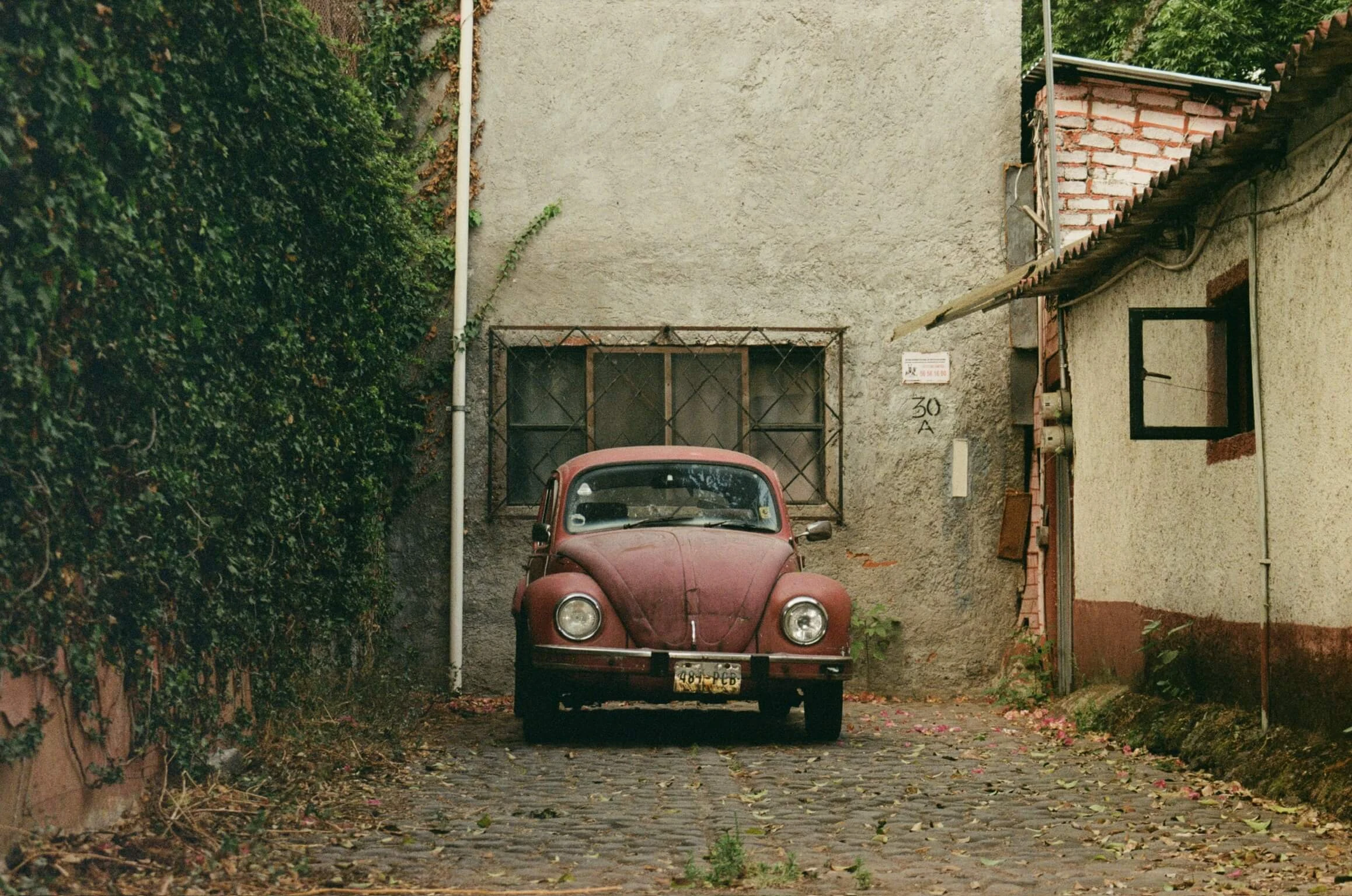 A red Volkswagen Beetle parked in a Mexico City courtyard
